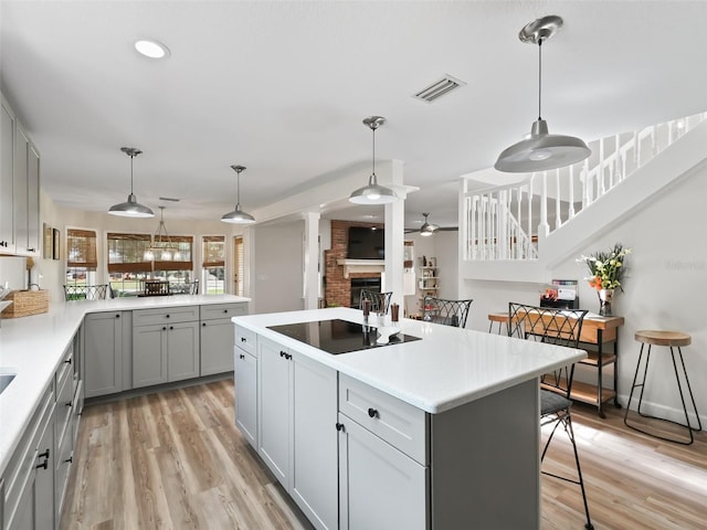 kitchen featuring a kitchen breakfast bar, pendant lighting, light hardwood / wood-style floors, and a brick fireplace