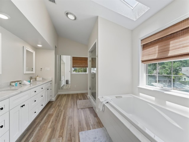 bathroom featuring lofted ceiling with skylight, wood-type flooring, shower with separate bathtub, and double sink vanity