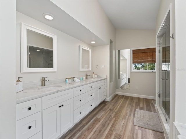 bathroom featuring wood-type flooring, lofted ceiling, an enclosed shower, and dual vanity