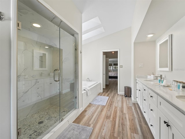 bathroom with wood-type flooring, plus walk in shower, lofted ceiling with skylight, and dual vanity