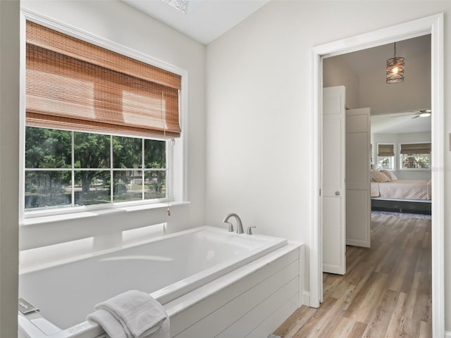 bathroom featuring hardwood / wood-style flooring, ceiling fan, and a bath