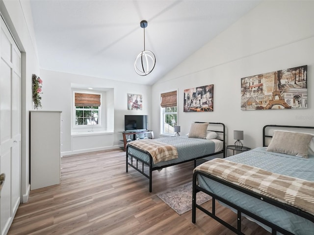 bedroom featuring light hardwood / wood-style floors, vaulted ceiling, and multiple windows