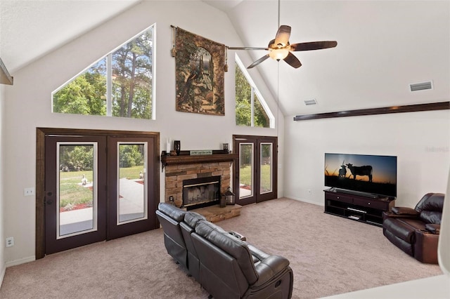 carpeted living room featuring high vaulted ceiling, french doors, ceiling fan, and a stone fireplace