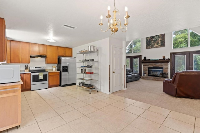 kitchen featuring a stone fireplace, a notable chandelier, light tile flooring, electric range, and stainless steel fridge with ice dispenser