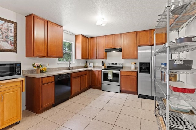 kitchen featuring sink, light tile floors, stainless steel appliances, and a textured ceiling