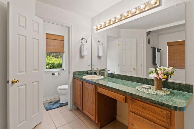 bathroom featuring dual vanity, toilet, tile flooring, and a textured ceiling