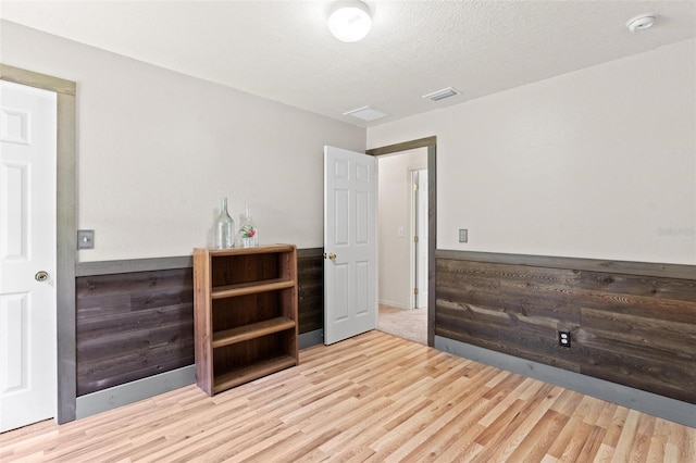 unfurnished room featuring light hardwood / wood-style flooring and a textured ceiling