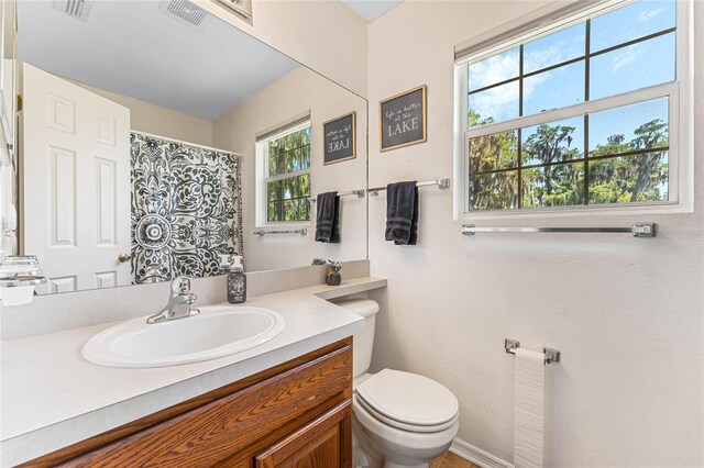 bathroom with a wealth of natural light, large vanity, and toilet