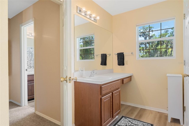 bathroom with wood-type flooring, plenty of natural light, and vanity with extensive cabinet space