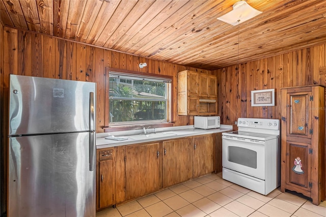 kitchen with white appliances, wooden walls, wood ceiling, sink, and light tile floors