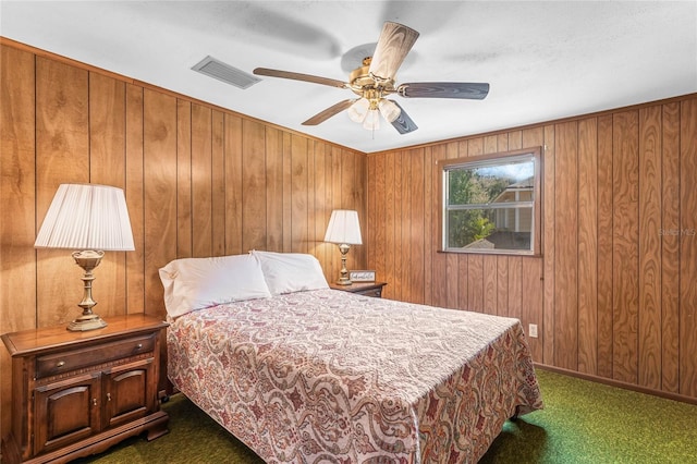 carpeted bedroom featuring wooden walls and ceiling fan