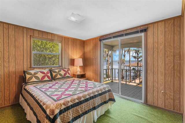 carpeted bedroom featuring wood walls and access to outside