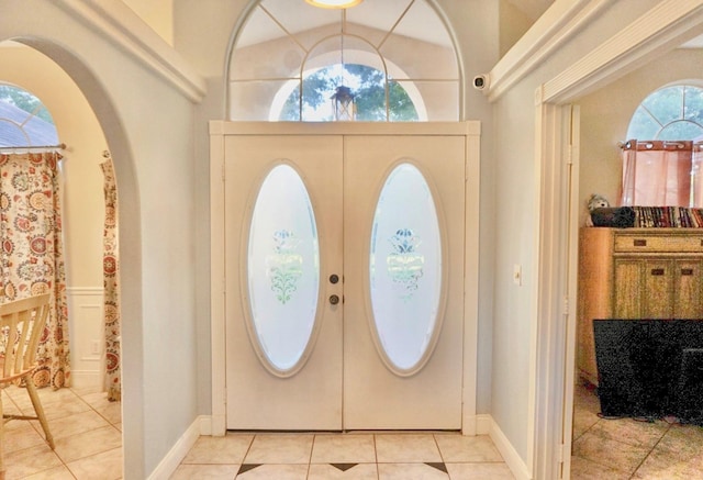 entrance foyer with french doors, light tile floors, and a towering ceiling