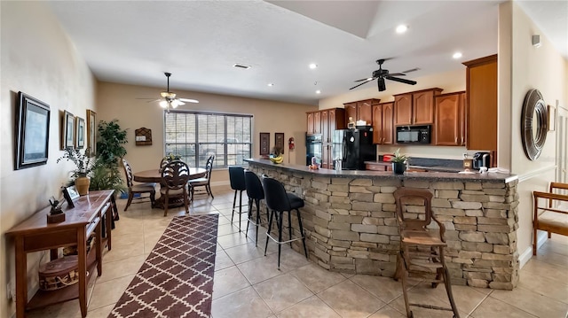 23321 N Buckhill Rd, Howey In The Hills, FL 34737 - kitchen with a ceiling fan, black appliances, a kitchen bar, brown cabinets, and a peninsula