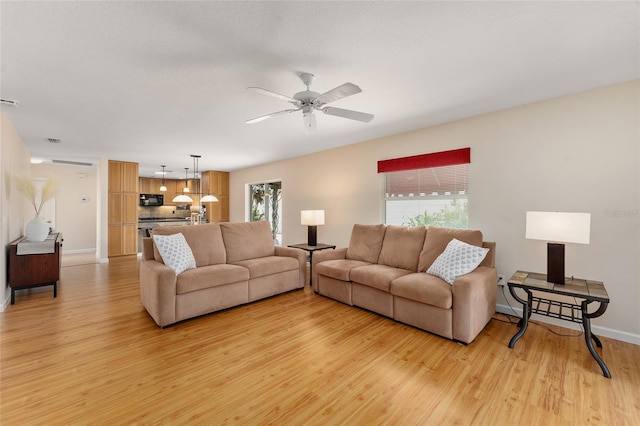 living room featuring plenty of natural light, light wood-type flooring, and ceiling fan