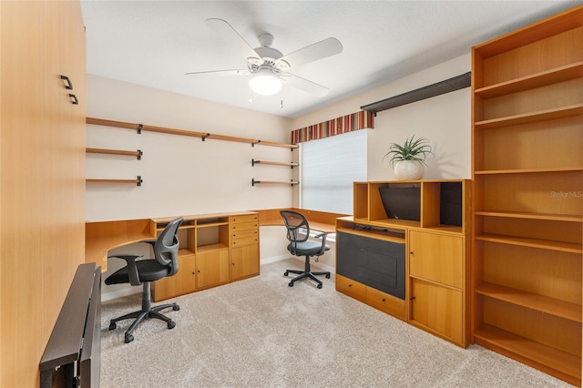 carpeted office featuring built in desk and ceiling fan