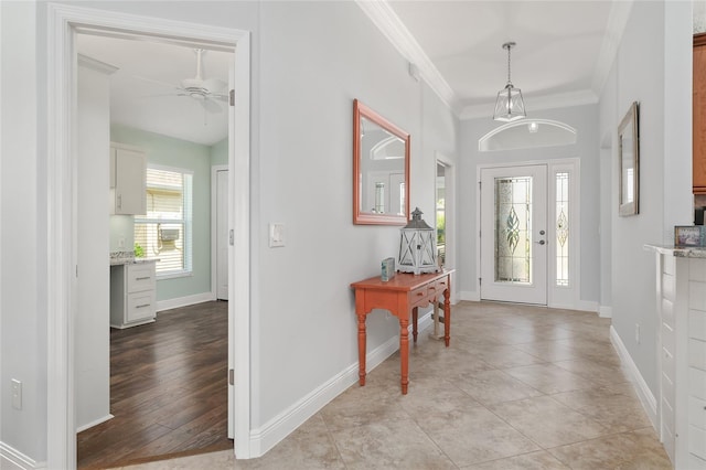 tiled entryway featuring ceiling fan and crown molding