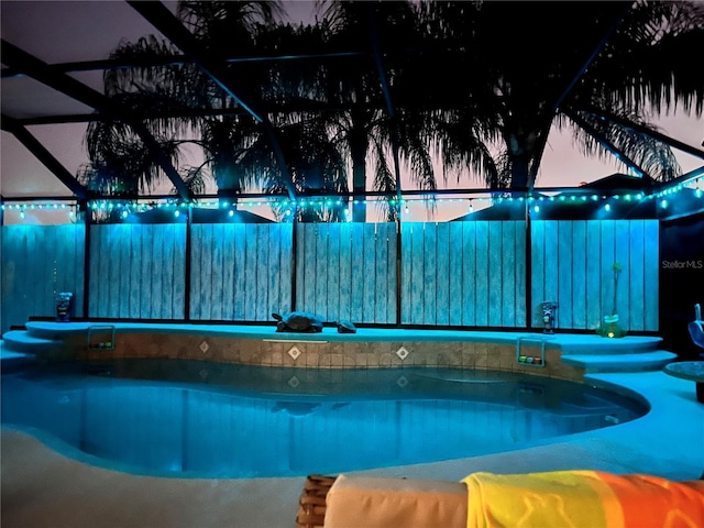 pool at dusk featuring glass enclosure