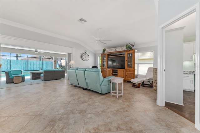 tiled living room with vaulted ceiling, ceiling fan, and a healthy amount of sunlight