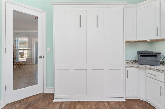 interior space with crown molding, white cabinets, dark hardwood / wood-style floors, and light stone counters