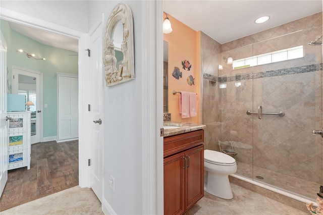 bathroom featuring toilet, a shower with shower door, hardwood / wood-style floors, and vanity