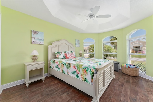 bedroom with ceiling fan, dark hardwood / wood-style flooring, and a raised ceiling