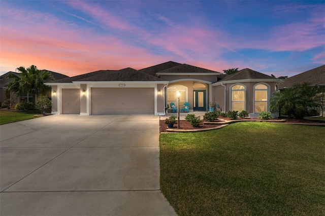 ranch-style home with a garage, concrete driveway, a front yard, and stucco siding