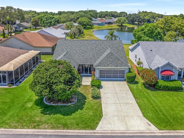 view of front of home with a front yard, a water view, a sunroom, and a garage