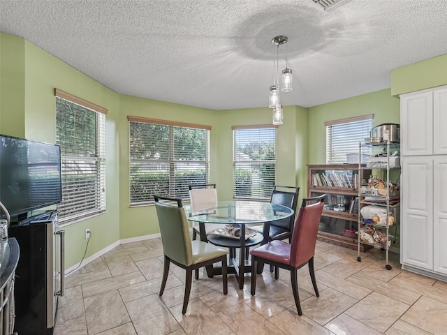 tiled dining area featuring plenty of natural light and a textured ceiling