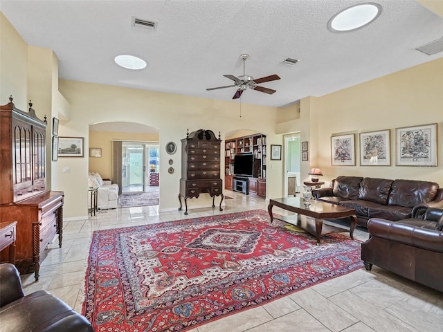 tiled living room featuring ceiling fan and a textured ceiling