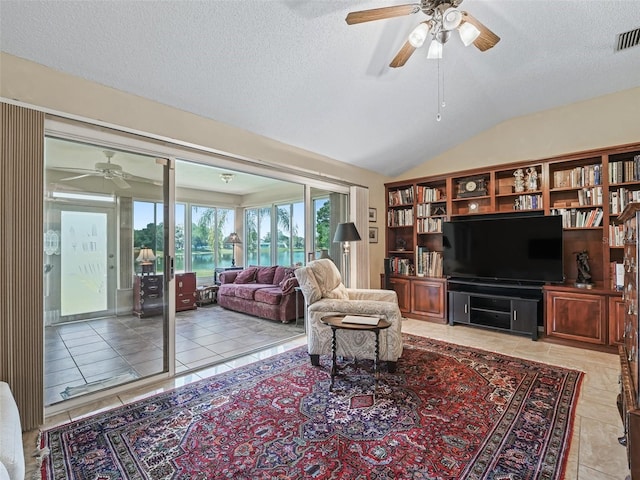 living room with vaulted ceiling, ceiling fan, light tile floors, and a textured ceiling