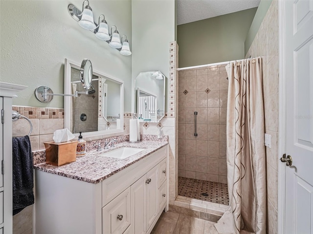 bathroom with tile walls, large vanity, tile flooring, a shower with curtain, and a textured ceiling