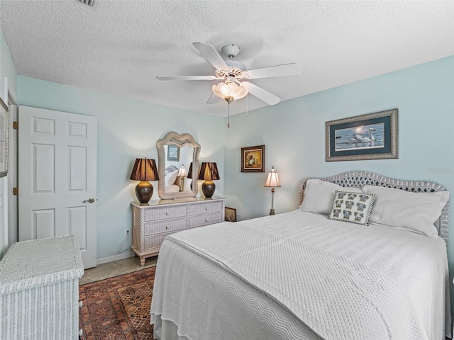 bedroom featuring dark tile floors, ceiling fan, and a textured ceiling