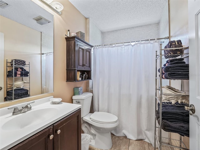 bathroom with tile flooring, vanity, toilet, and a textured ceiling