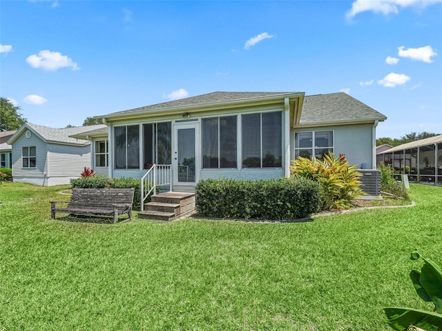 rear view of property with central AC, a yard, and a sunroom