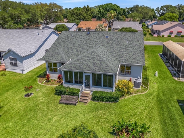 rear view of property with central AC unit, a yard, and a sunroom