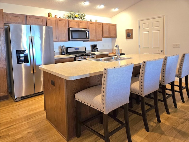 kitchen with a center island with sink, light hardwood / wood-style floors, a kitchen breakfast bar, and appliances with stainless steel finishes