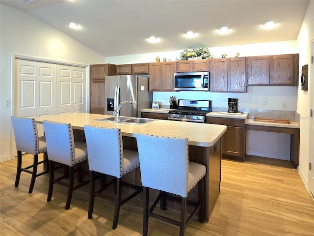 kitchen featuring appliances with stainless steel finishes, sink, light hardwood / wood-style floors, and an island with sink