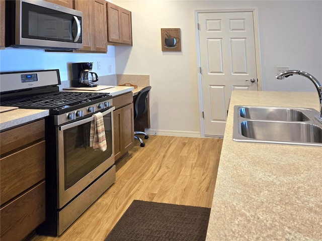 kitchen featuring appliances with stainless steel finishes, sink, and light wood-type flooring