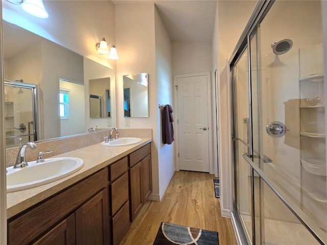 bathroom with wood-type flooring, an enclosed shower, double sink, and large vanity