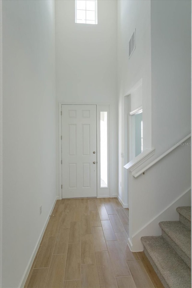 entrance foyer featuring light wood-type flooring and a towering ceiling