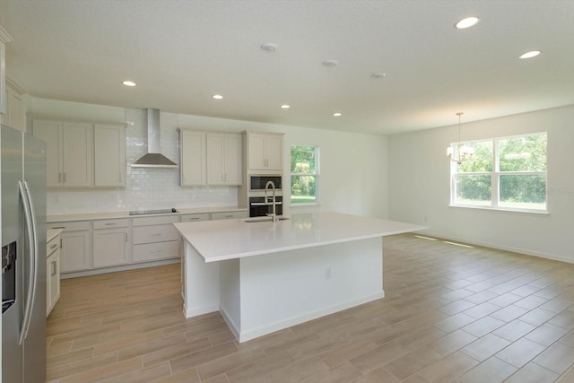 kitchen with wall chimney exhaust hood, tasteful backsplash, appliances with stainless steel finishes, and a wealth of natural light