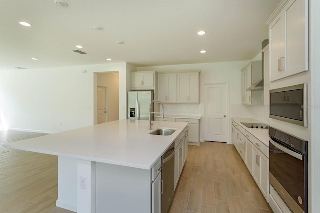 kitchen featuring a spacious island, backsplash, appliances with stainless steel finishes, sink, and light hardwood / wood-style floors