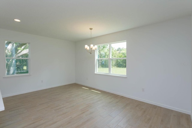 unfurnished room featuring light hardwood / wood-style floors and an inviting chandelier