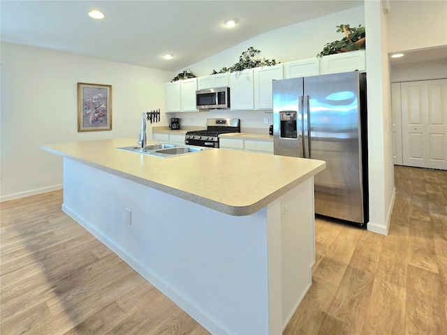 kitchen featuring white cabinets, stainless steel appliances, light wood-type flooring, and an island with sink