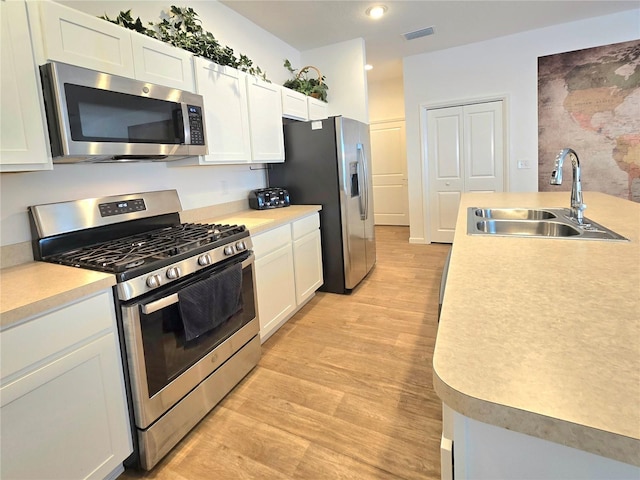 kitchen with white cabinets, sink, light hardwood / wood-style floors, and stainless steel appliances