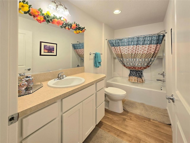 full bathroom featuring wood-type flooring, shower / tub combo, vanity with extensive cabinet space, and toilet