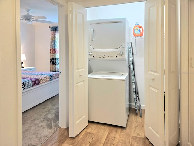 laundry area with ceiling fan, light wood-type flooring, and stacked washing maching and dryer