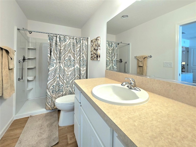 bathroom with large vanity, a textured ceiling, hardwood / wood-style floors, toilet, and curtained shower