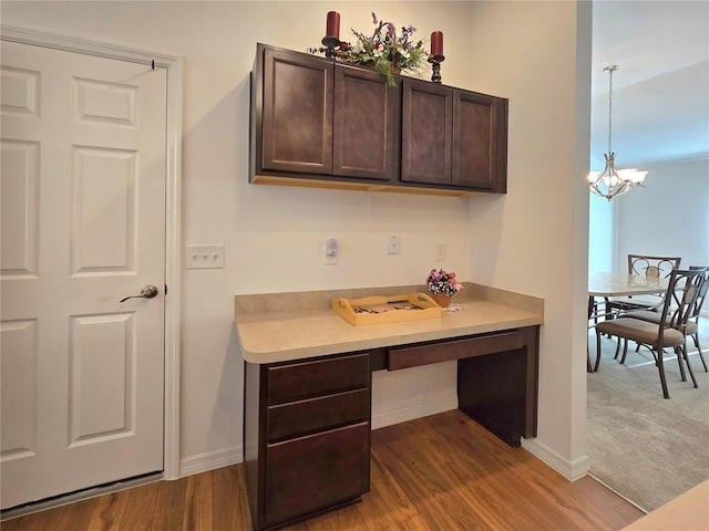 kitchen with a chandelier, wood-type flooring, and dark brown cabinets